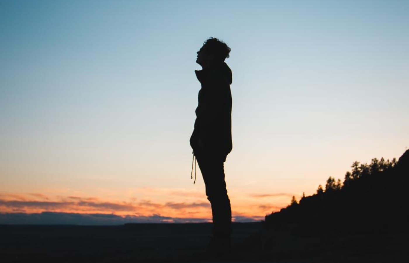 A person standing on a hillside at sunset