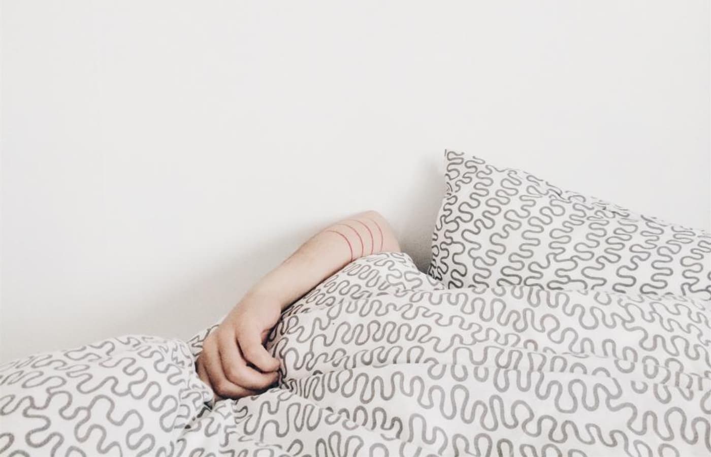 A hand resting on soft white bedding