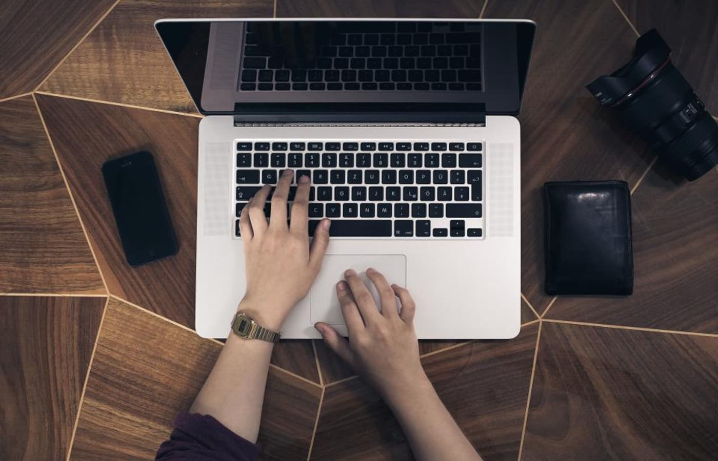 Hands typing on a laptop on a wooden desk